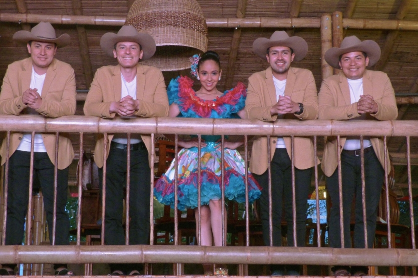 Fotografía de Astrid Carolina con sus músicos en un balcón y traje típico