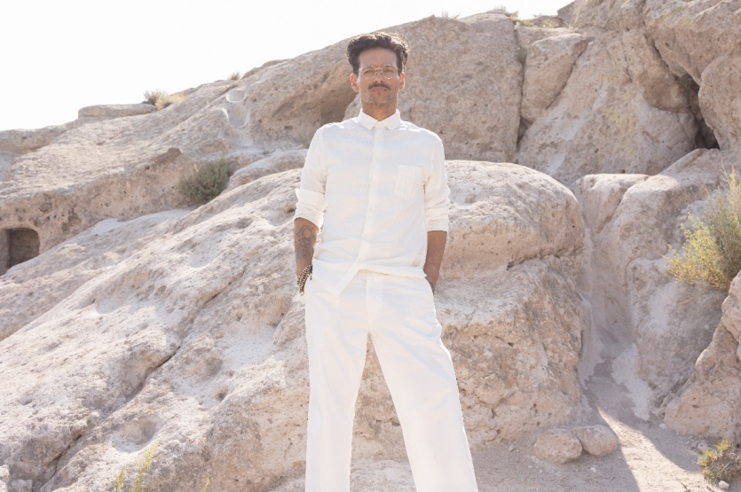 Fotografía de Draco Rosa vestido de blanco al fondo unas rocas