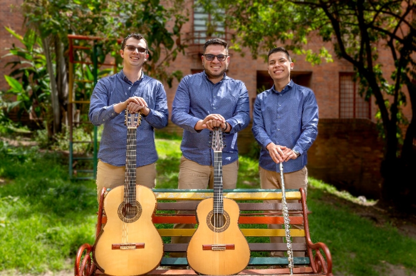 Fotografía de músicos Tr3s en Uno con los instrumentos en una banca de parque al fondo arboles