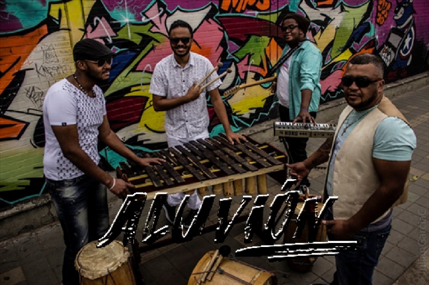 Fotografía del grupo Aluvión tocando marimba al fondo se ve un mural colorido